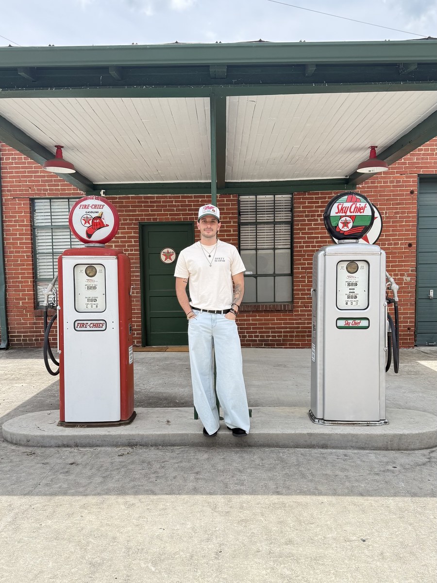 Paulo Loyo, UGC creator and filmmaker, standing between vintage gas pumps